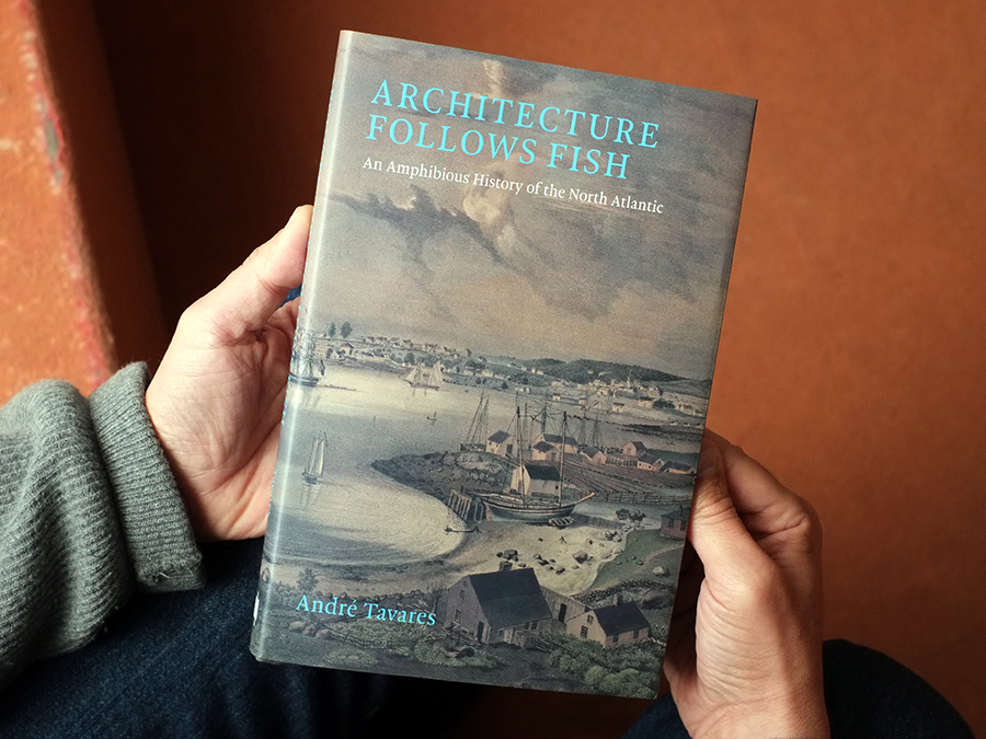 Hands holding a hardcover book. The book’s cover reads Architecture Follows Fish